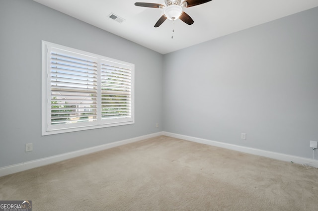 spare room featuring baseboards, visible vents, ceiling fan, and light colored carpet