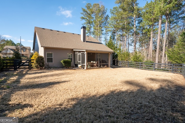 back of property with a shingled roof, a chimney, a fenced backyard, and a sunroom