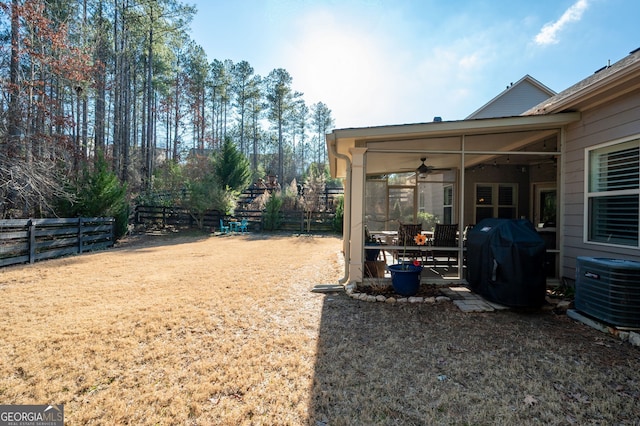 view of yard featuring a sunroom, fence, and central AC unit