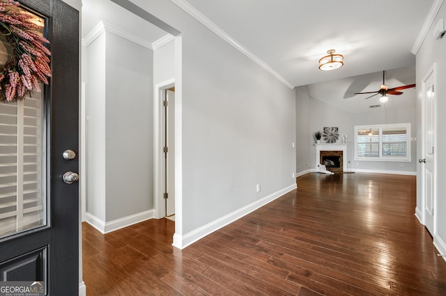 interior space featuring baseboards, a ceiling fan, ornamental molding, wood finished floors, and a fireplace