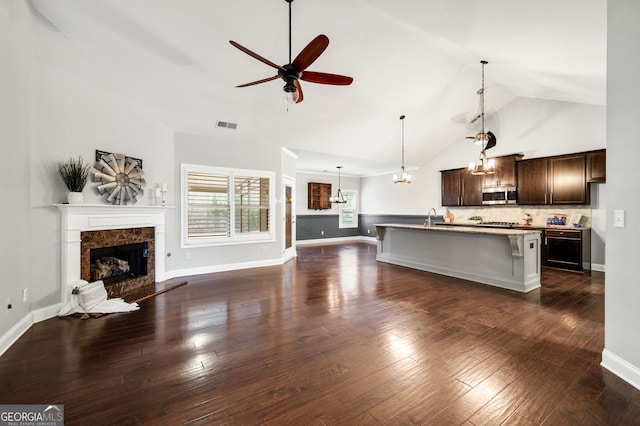 unfurnished living room featuring visible vents, a ceiling fan, dark wood-style floors, a fireplace, and a sink