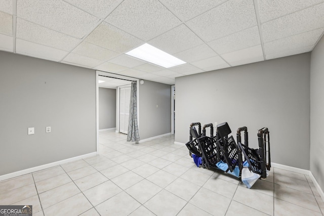 basement with a paneled ceiling and light tile patterned floors