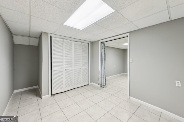 interior space featuring light tile patterned floors, a drop ceiling, and a closet