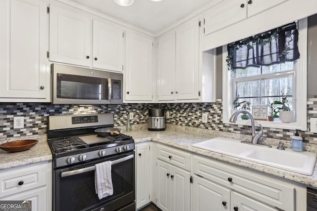 kitchen with stainless steel appliances, white cabinetry, sink, and decorative backsplash