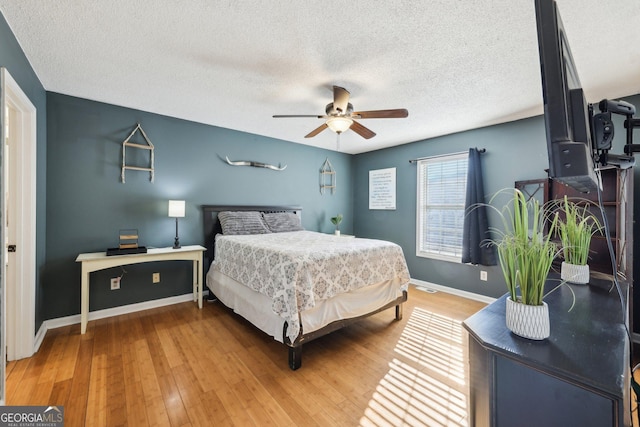 bedroom featuring ceiling fan, wood-type flooring, and a textured ceiling