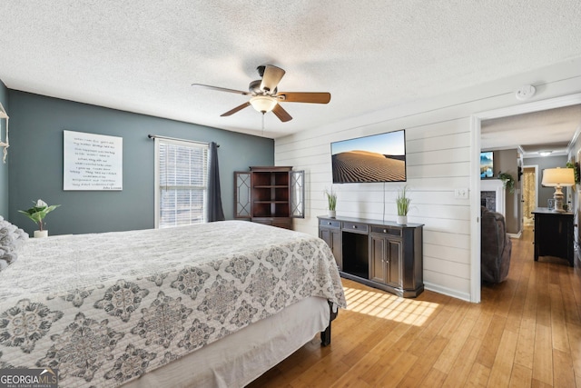 bedroom featuring ceiling fan, hardwood / wood-style floors, and a textured ceiling