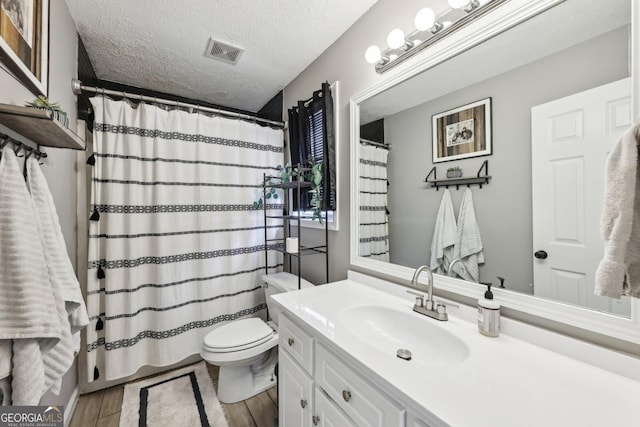 bathroom with hardwood / wood-style floors, vanity, walk in shower, toilet, and a textured ceiling