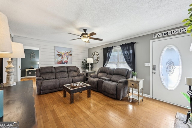 living room with crown molding, ceiling fan, wood-type flooring, and a textured ceiling