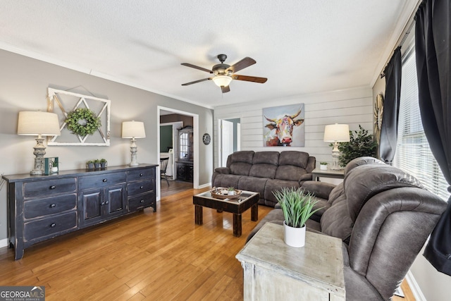 living room featuring ceiling fan, ornamental molding, hardwood / wood-style floors, and a textured ceiling