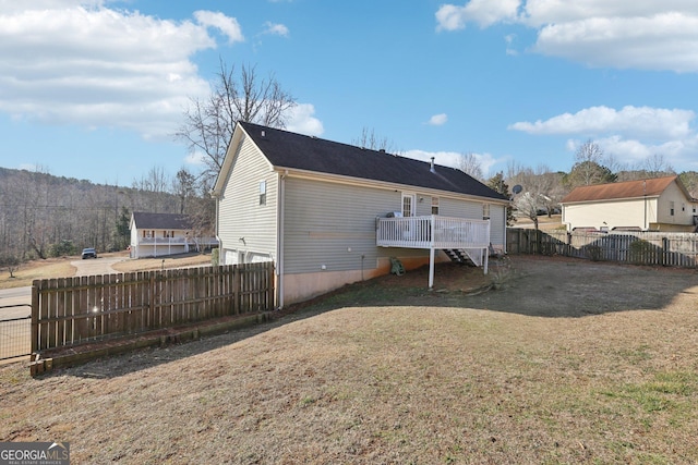 back of house with a wooden deck and a lawn