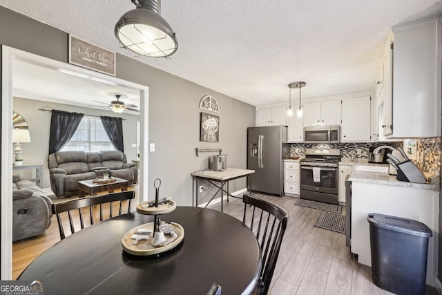 kitchen featuring tasteful backsplash, appliances with stainless steel finishes, light hardwood / wood-style flooring, and white cabinets