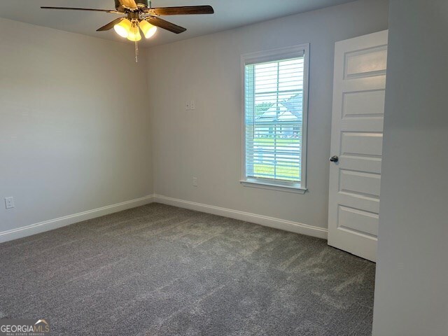 carpeted spare room with ceiling fan