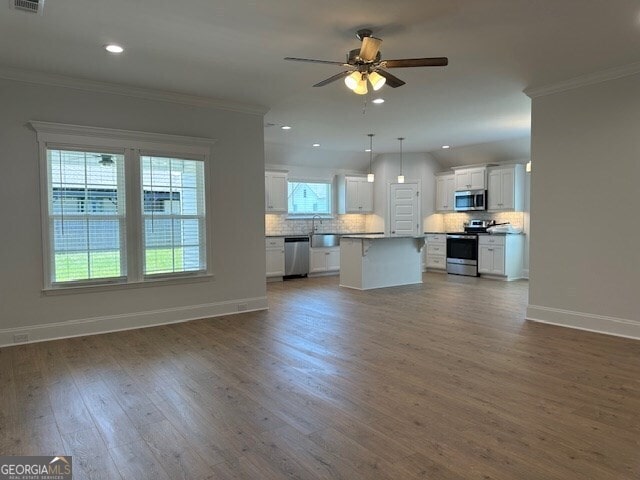 unfurnished living room featuring crown molding, ceiling fan, and dark hardwood / wood-style flooring