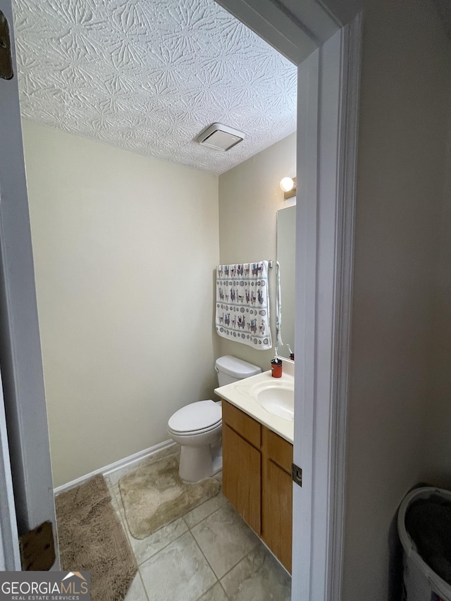 bathroom featuring vanity, toilet, and a textured ceiling