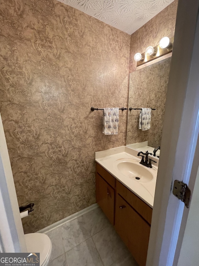 bathroom with vanity, tile patterned flooring, toilet, and a textured ceiling