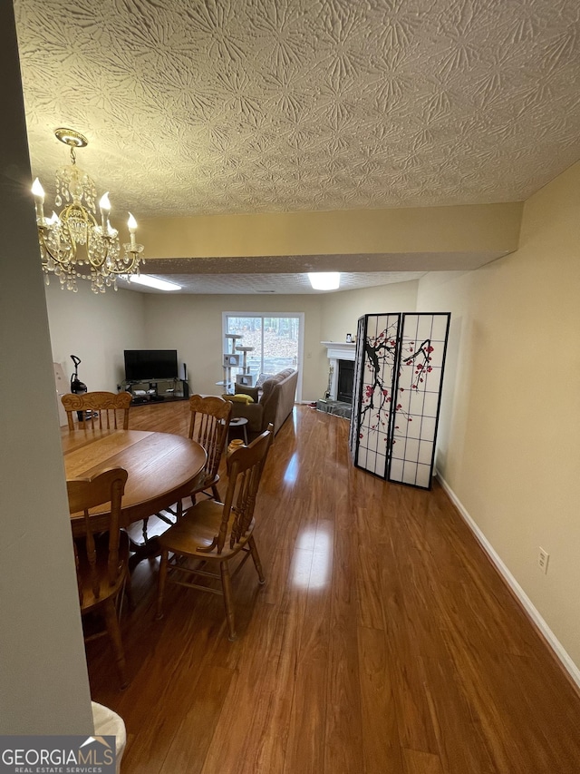 dining area with a chandelier, hardwood / wood-style floors, and a textured ceiling