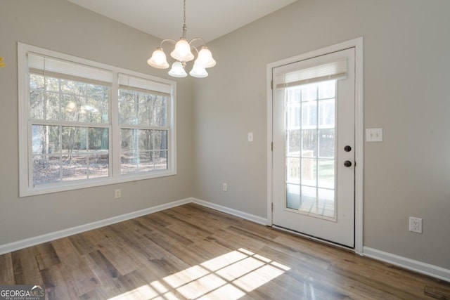 unfurnished dining area with a notable chandelier and light wood-type flooring