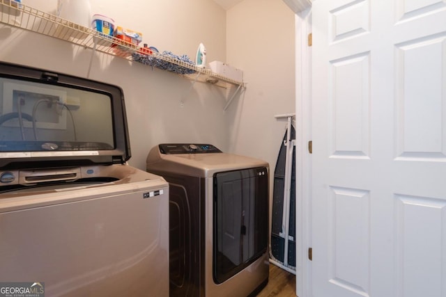 clothes washing area featuring hardwood / wood-style flooring and washing machine and dryer