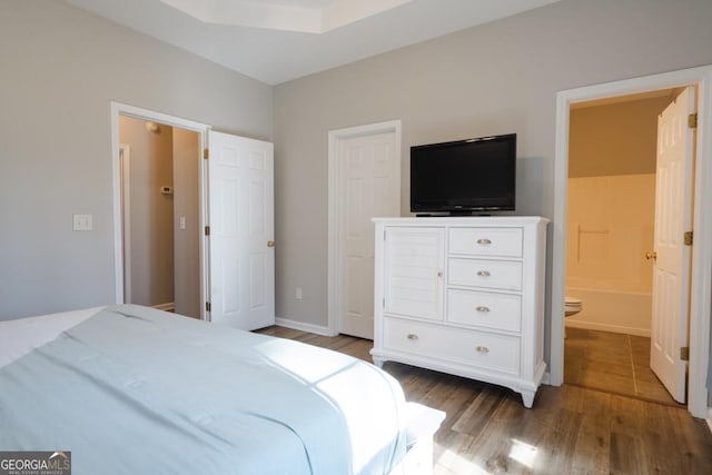 bedroom featuring ensuite bathroom and dark hardwood / wood-style flooring