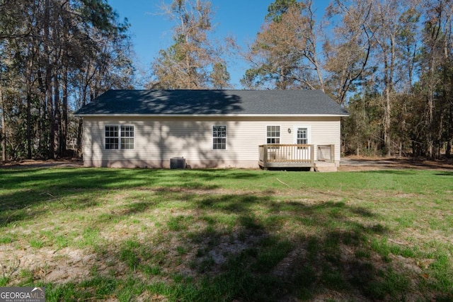 rear view of property with cooling unit, a deck, and a lawn