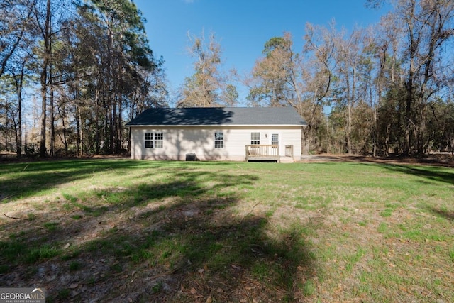 back of property featuring a wooden deck and a lawn