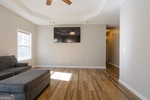 living room featuring a raised ceiling, hardwood / wood-style floors, and ceiling fan