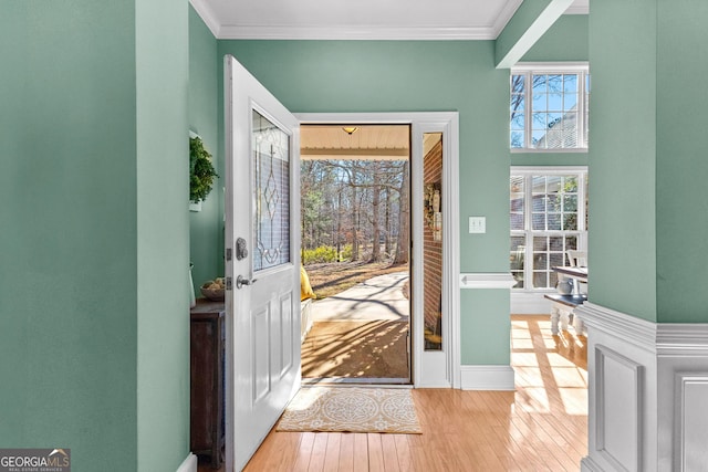 foyer with crown molding and light hardwood / wood-style floors