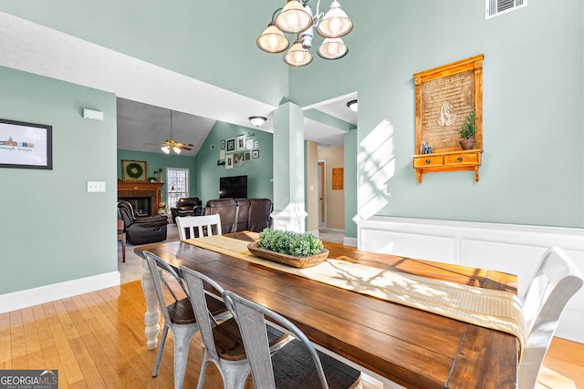 dining room featuring ceiling fan with notable chandelier, lofted ceiling, and light hardwood / wood-style floors