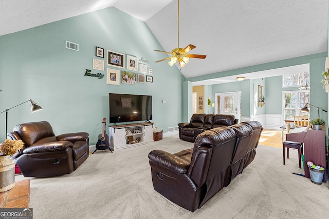 carpeted living room with ceiling fan and high vaulted ceiling