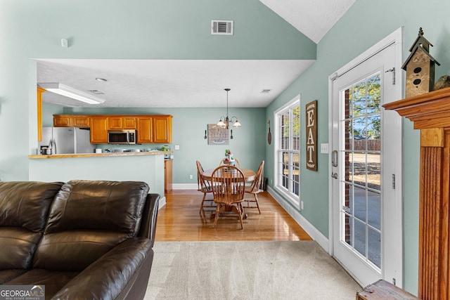 living room with lofted ceiling, a notable chandelier, and light hardwood / wood-style flooring