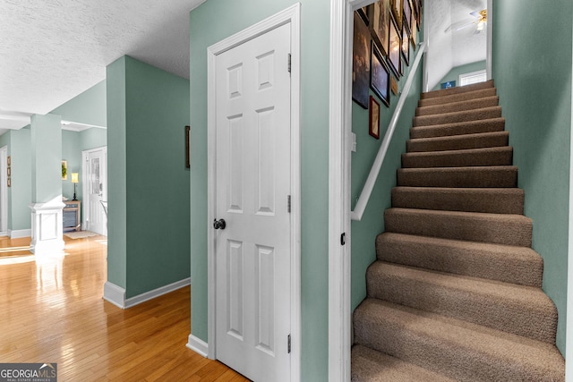 stairs with wood-type flooring and a textured ceiling