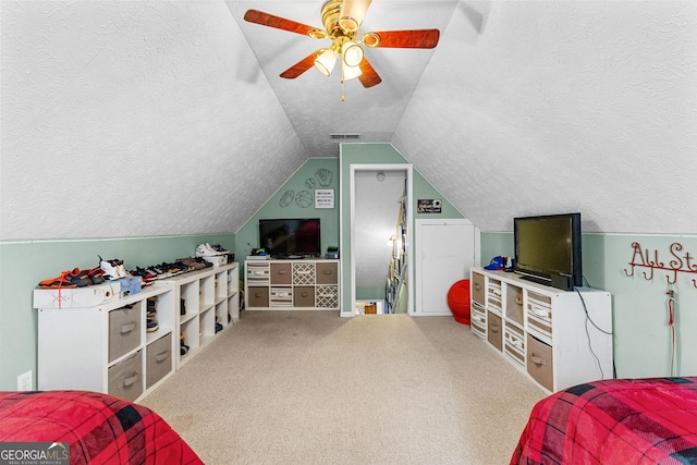 bedroom with ceiling fan, lofted ceiling, carpet floors, and a textured ceiling