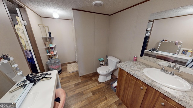 231 Canady Bridge Rd, Twin City, GA 30471 - bathroom with wood finished floors, vanity, toilet, a textured ceiling, and ornamental molding