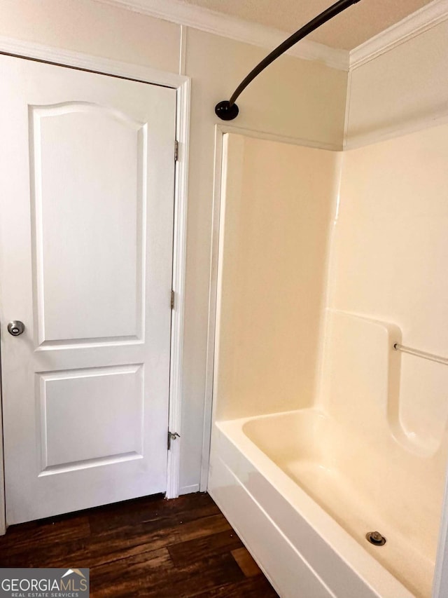 bathroom featuring hardwood / wood-style flooring,  shower combination, and ornamental molding