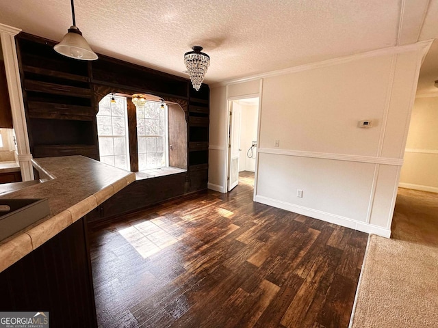 unfurnished dining area with crown molding, a textured ceiling, and dark hardwood / wood-style flooring