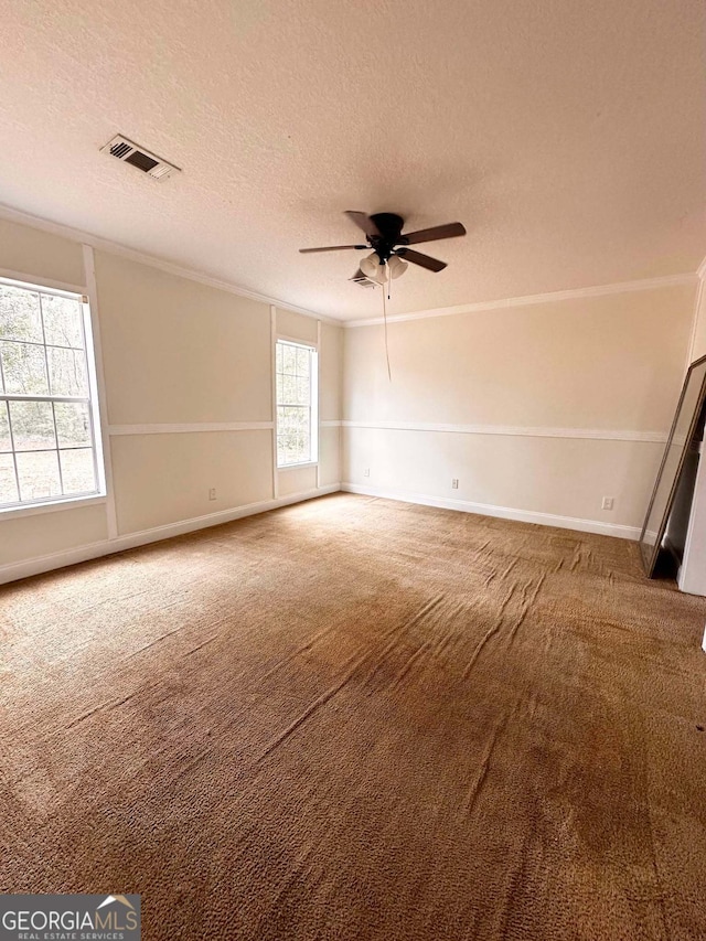 unfurnished room with ceiling fan, ornamental molding, carpet flooring, and a textured ceiling