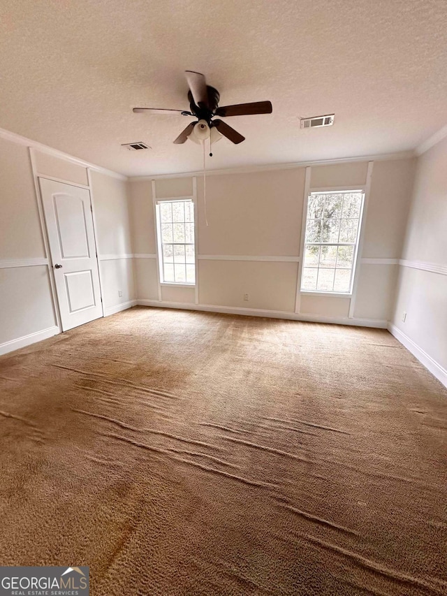 spare room featuring ceiling fan, ornamental molding, a textured ceiling, and carpet