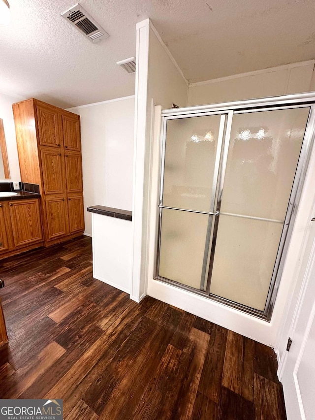 bathroom featuring hardwood / wood-style flooring, an enclosed shower, and a textured ceiling