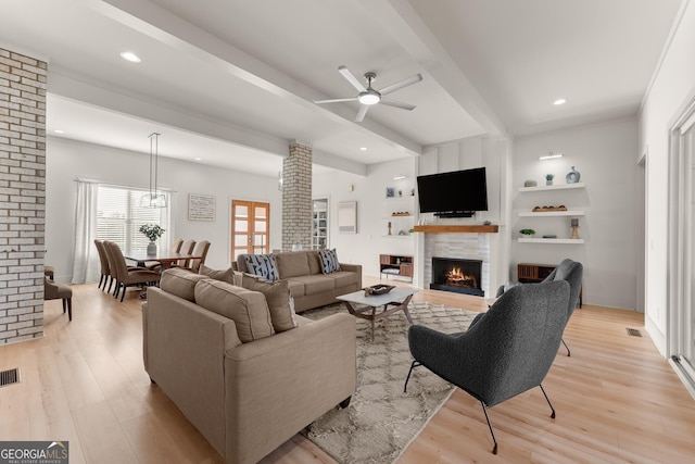 living room featuring light hardwood / wood-style flooring, built in features, beamed ceiling, ceiling fan, and decorative columns