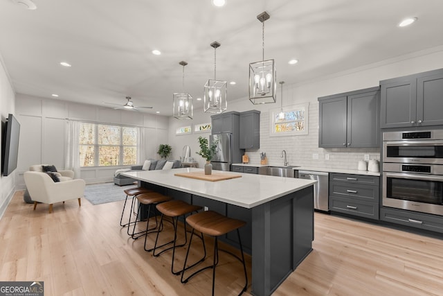 kitchen with appliances with stainless steel finishes, a kitchen bar, a kitchen island, and gray cabinetry