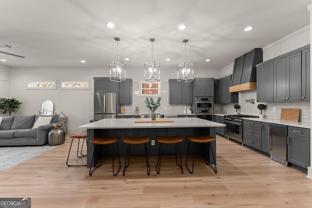 kitchen featuring gray cabinets, a center island, appliances with stainless steel finishes, and custom range hood