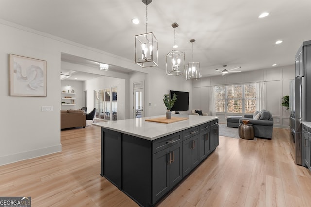 kitchen with crown molding, decorative light fixtures, a center island, light hardwood / wood-style flooring, and ceiling fan