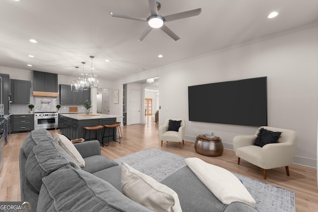 living room featuring crown molding, sink, ceiling fan with notable chandelier, and light hardwood / wood-style floors