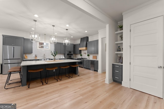 kitchen featuring gray cabinets, a kitchen bar, custom exhaust hood, a center island, and stainless steel appliances