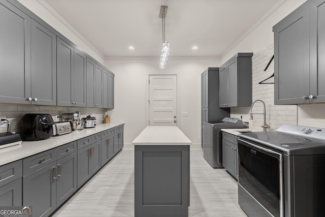 kitchen featuring sink, crown molding, gray cabinets, separate washer and dryer, and decorative light fixtures