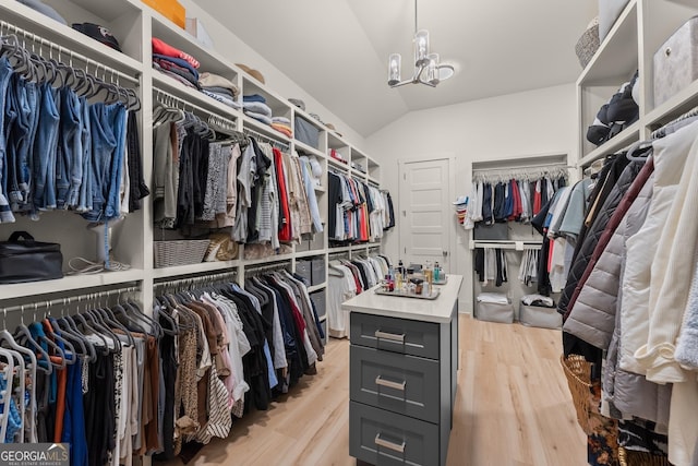 spacious closet with lofted ceiling, light hardwood / wood-style floors, and an inviting chandelier