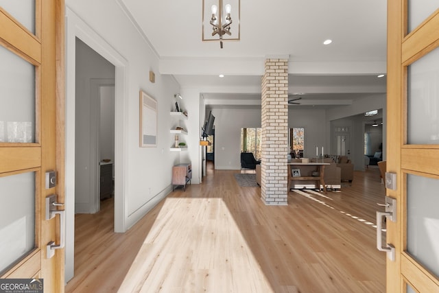 entrance foyer featuring ornate columns, beamed ceiling, a notable chandelier, light hardwood / wood-style floors, and crown molding