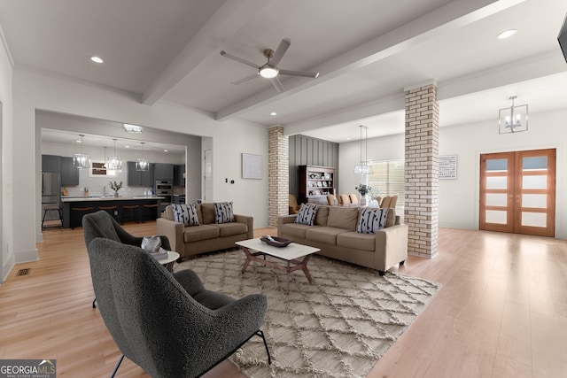 living room featuring beamed ceiling, light hardwood / wood-style floors, french doors, and ornate columns