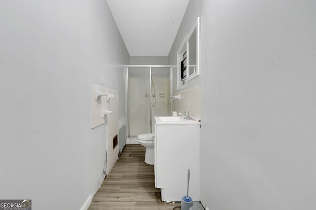 bathroom featuring walk in shower, toilet, hardwood / wood-style floors, and tile walls