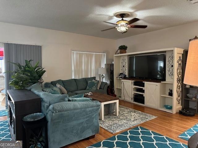 living room featuring ceiling fan, hardwood / wood-style floors, and a textured ceiling